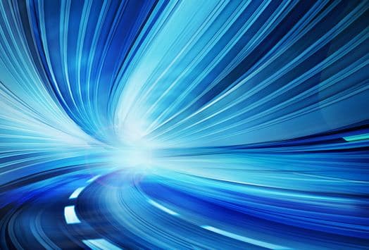 Blue light trails along a road curving through a tunnel