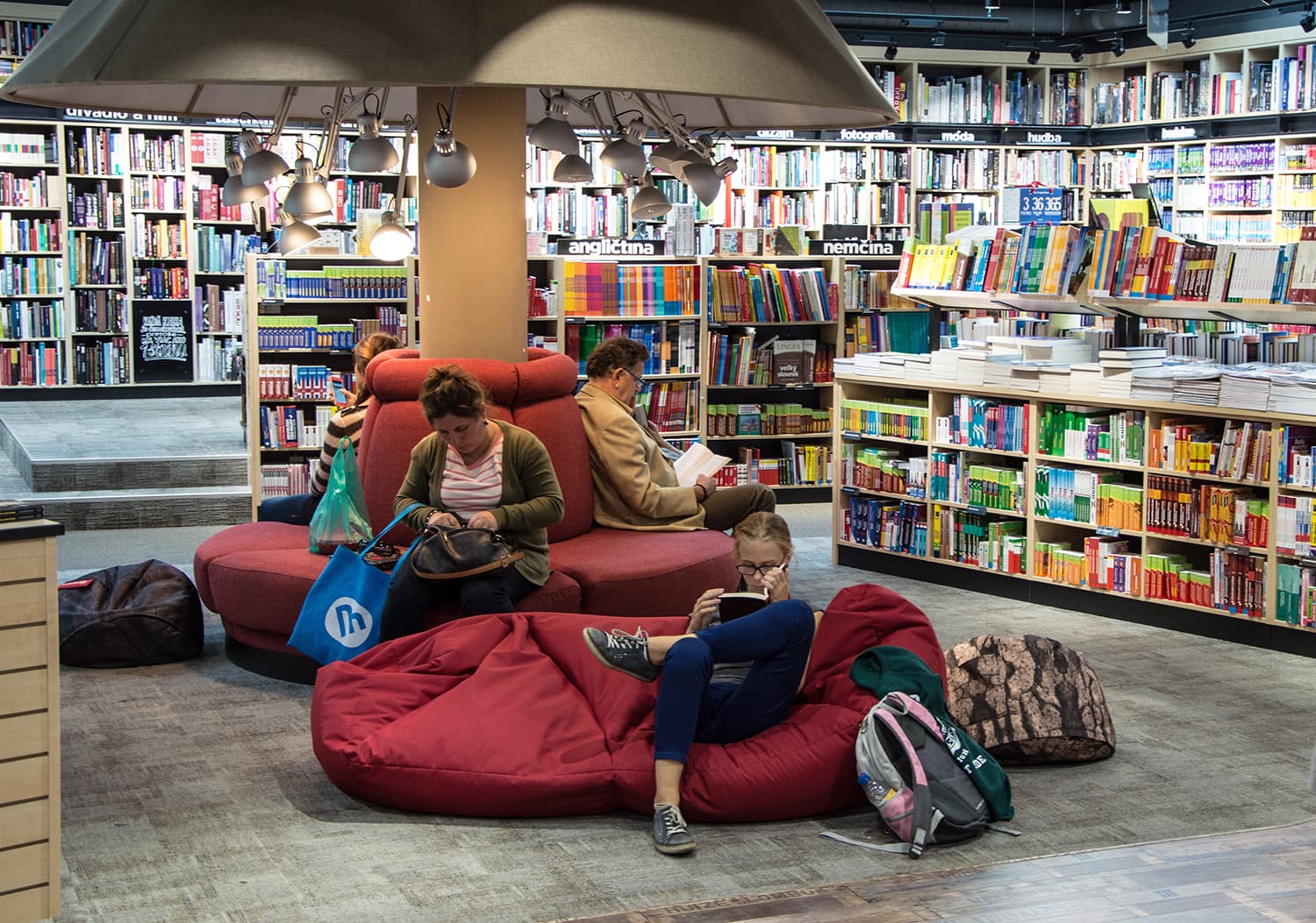 Readers on bean bags and a red sofa among the shelves of a bookshop